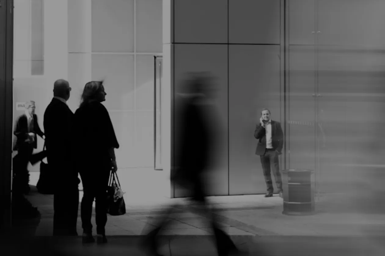 Black and white image of businesspeople standing and walking in a modern urban setting.