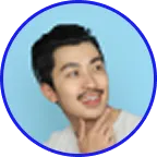 Young man with mustache smiling and touching his chin against a light blue background.