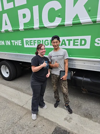 Happy customer standing with Urban Moving team member in front of moving truck in Los Angeles