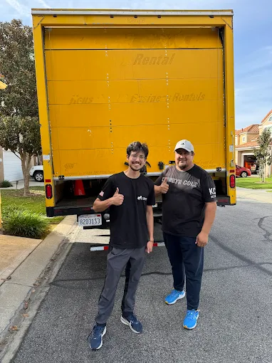 Happy customer standing behind Urban Moving truck after a successful move in Los Angeles