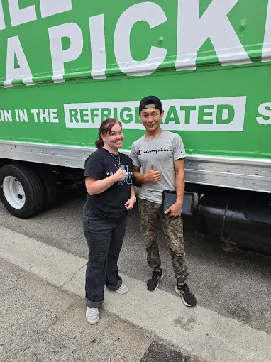Happy customer standing with Urban Moving team member in front of moving truck in Los Angeles