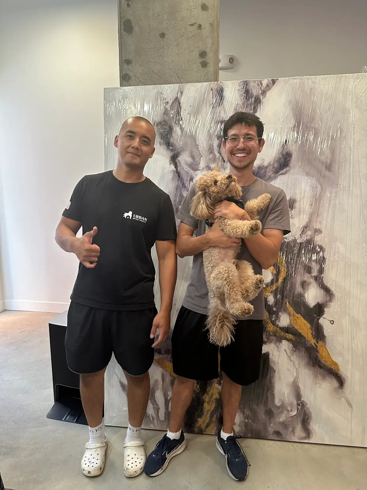 Happy customers in Los Angeles with Urban Moving team after a smooth and stress-free residential move, posing with their dog in their new home.