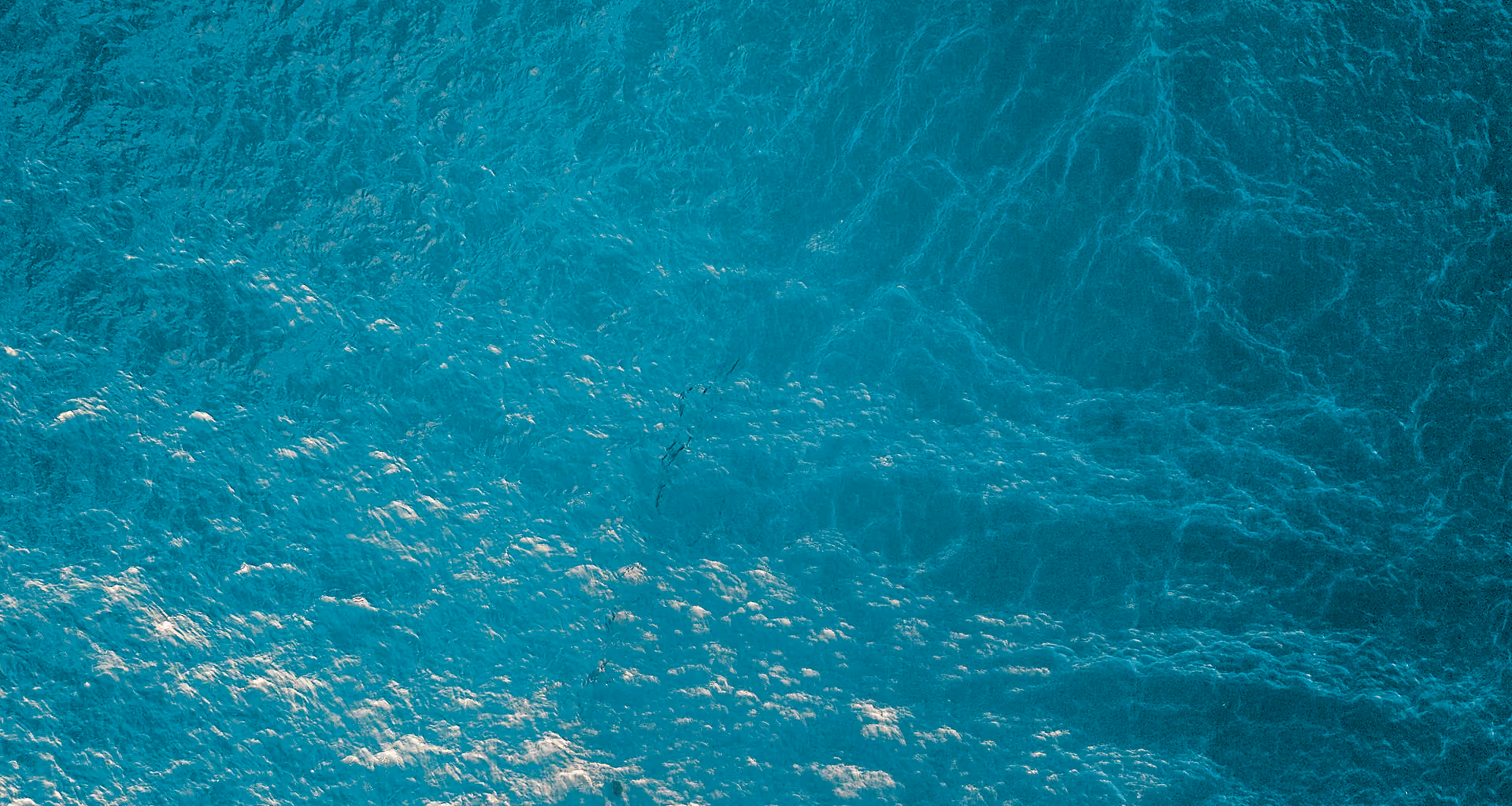 Close-up view of turquoise water surface with gentle ripples and light reflections.