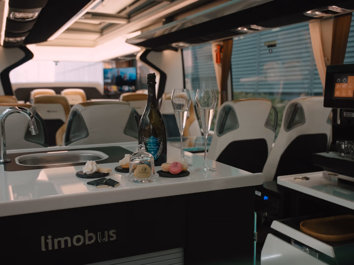 Limobus interior with champagne, flutes, macarons and chocolates — Moveolux luxury limobus and limo bus rental.