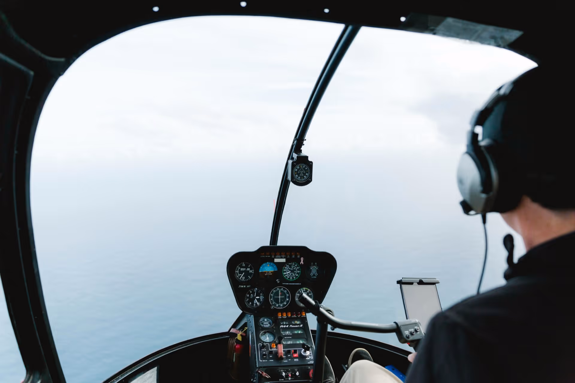 Private helicopter in flight over a scenic coastline — Moveolux helicopter rental service.