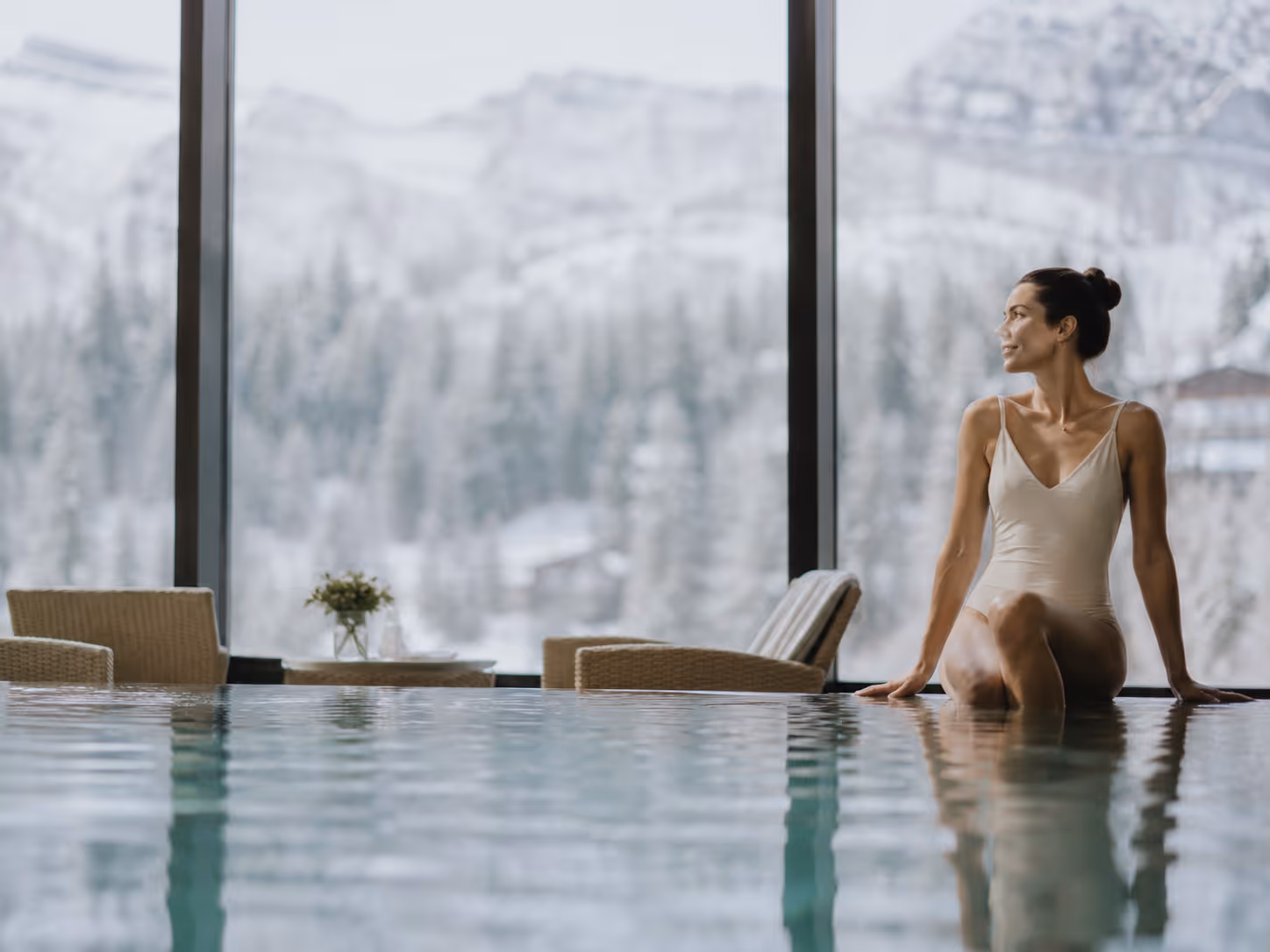 Guest at a luxury indoor pool with mountain views — wellness experience arranged by Moveolux lifestyle service.