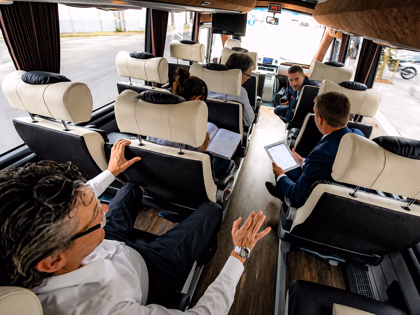 Business executives working on board a luxury coach — corporate travel service by Moveolux for high-demand organizations.