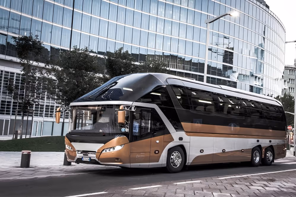 Modern black and bronze luxury coach bus parked on a city street near reflective glass buildings.