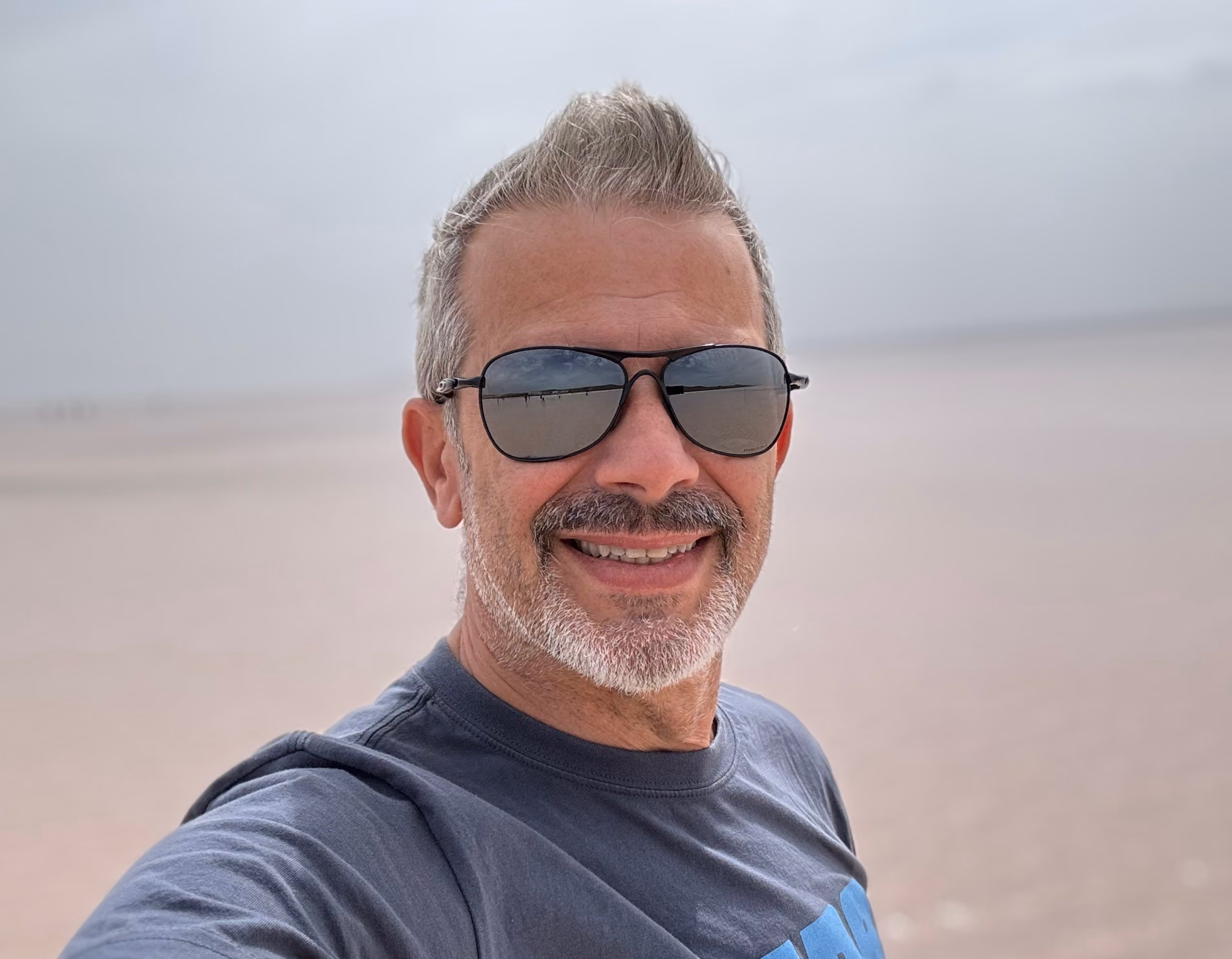 Alessandro Mapelli, CEO di Moveolux, sorridente, con barba e capelli grigi, occhiali da sole e maglietta scura. Servizi di viaggi su misura Moveolux.