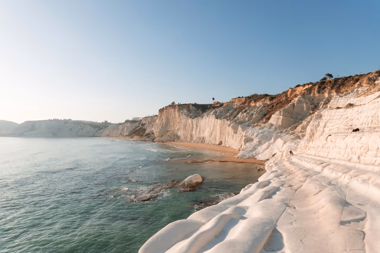 White limestone cliffs and rock formations along a calm coastal beach in Sicily, a destination for Moveolux yacht charter.