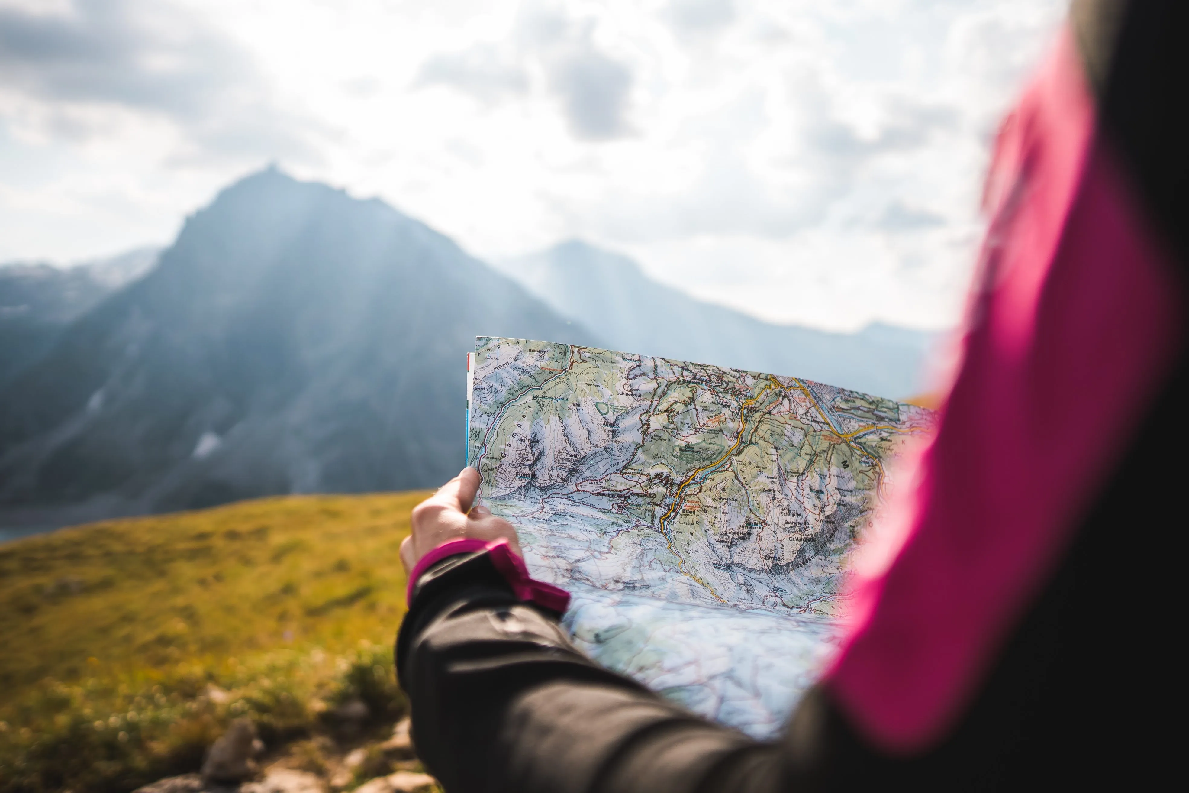 Person holding a detailed topographic map with a mountain landscape in the background.