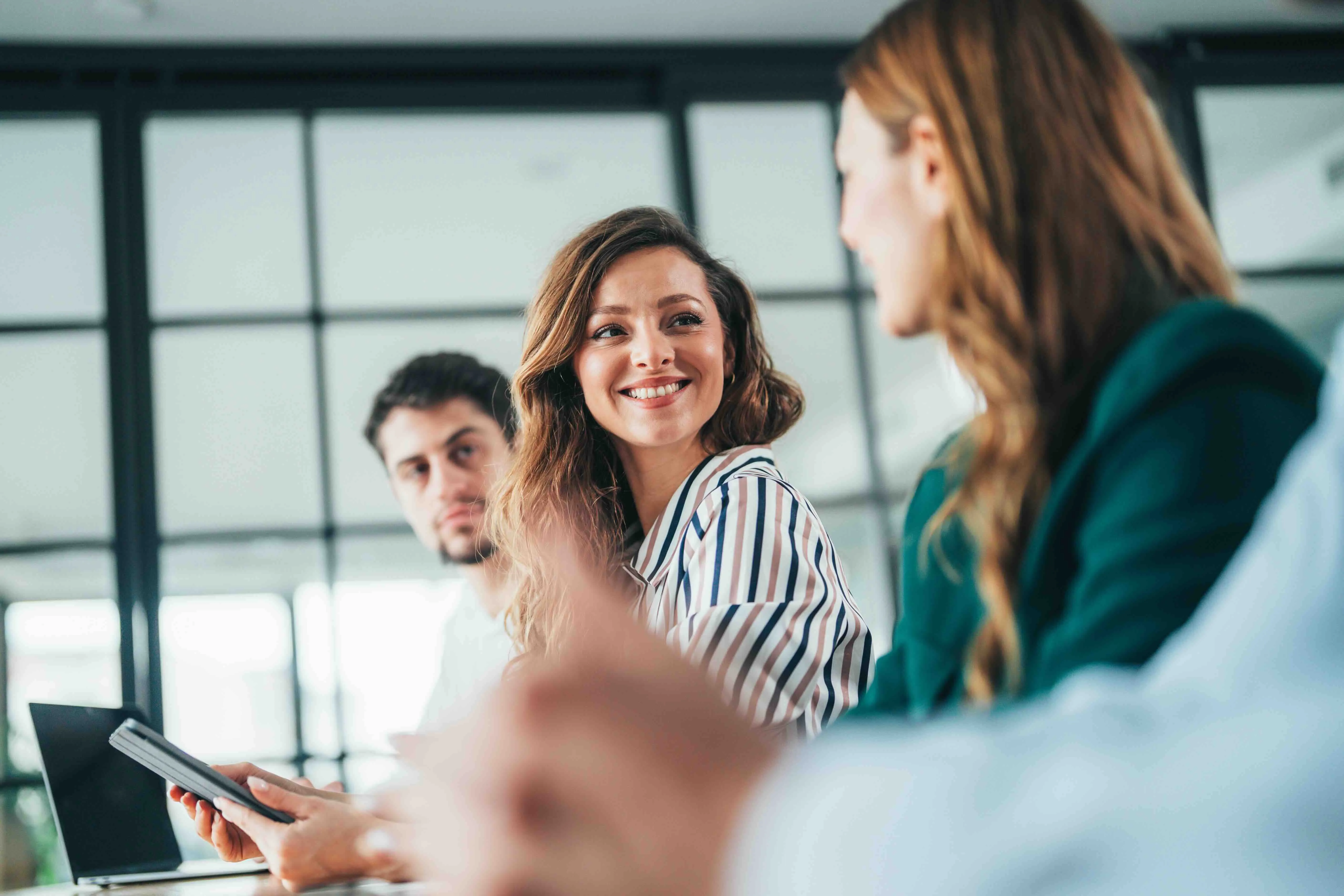 Two women smiling and collaborating in a modern office environment