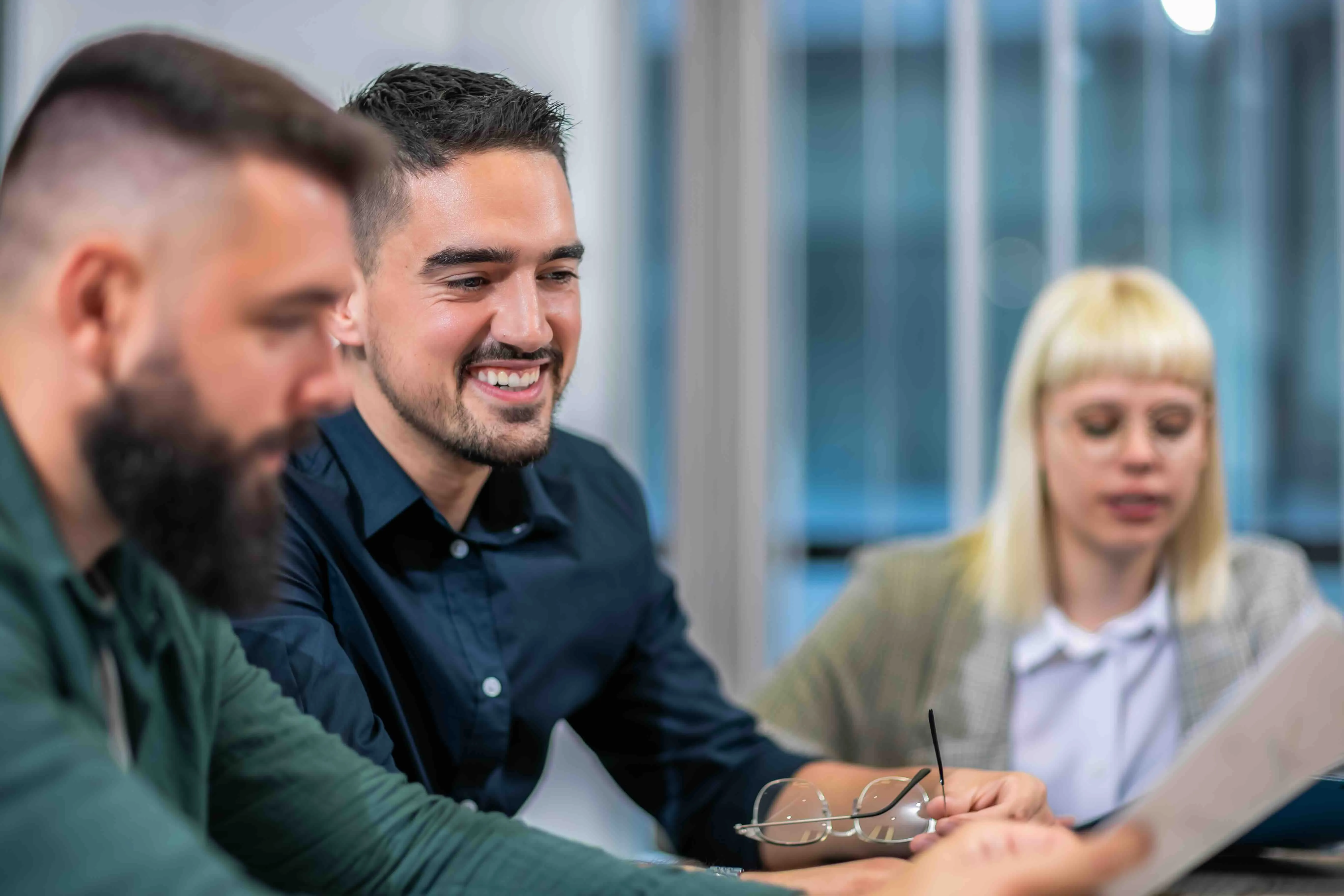 Three colleagues reviewing documents during a meeting in an office.