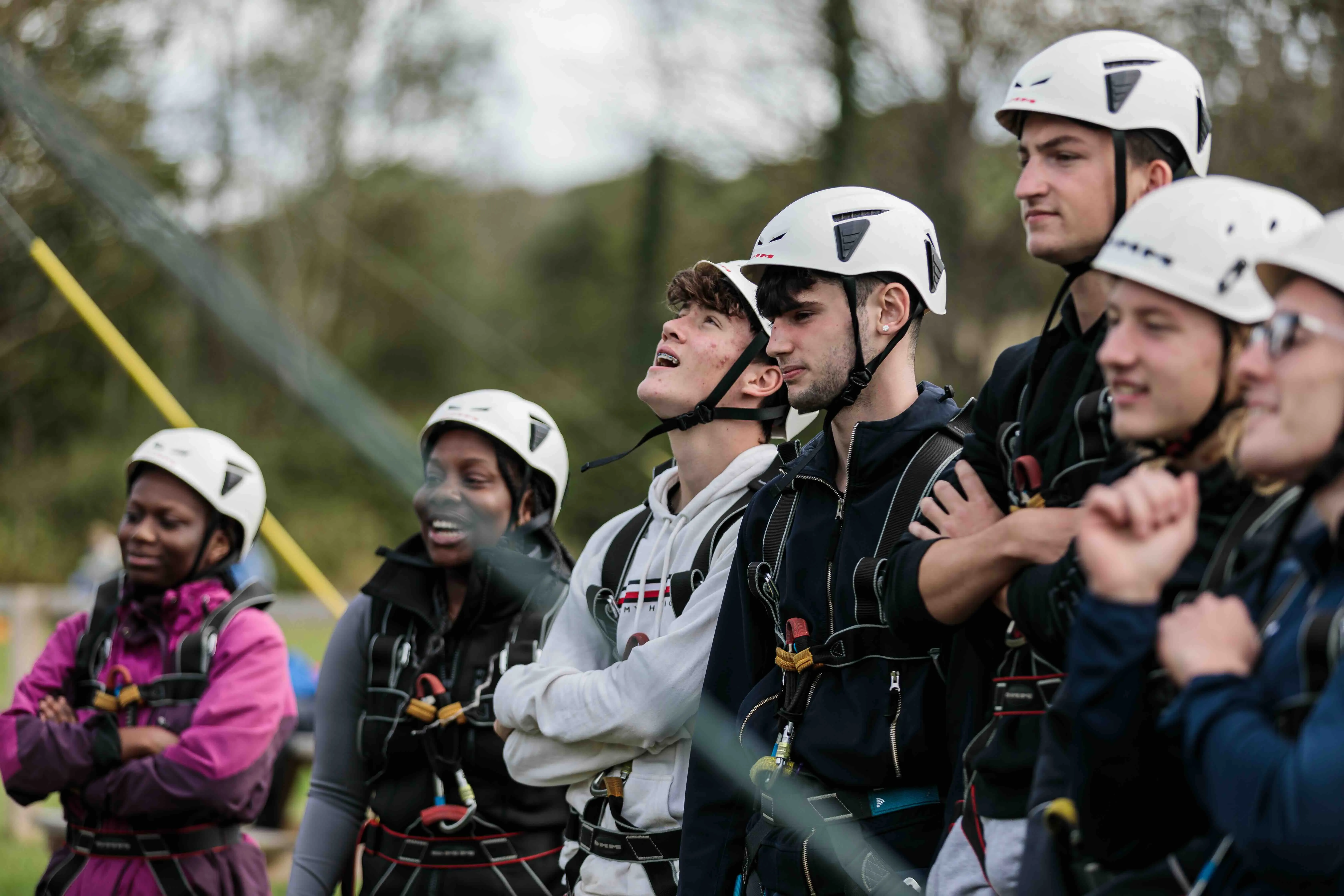 A group of apprentices wearing safety helmets during an outdoor climbing or adventure activity