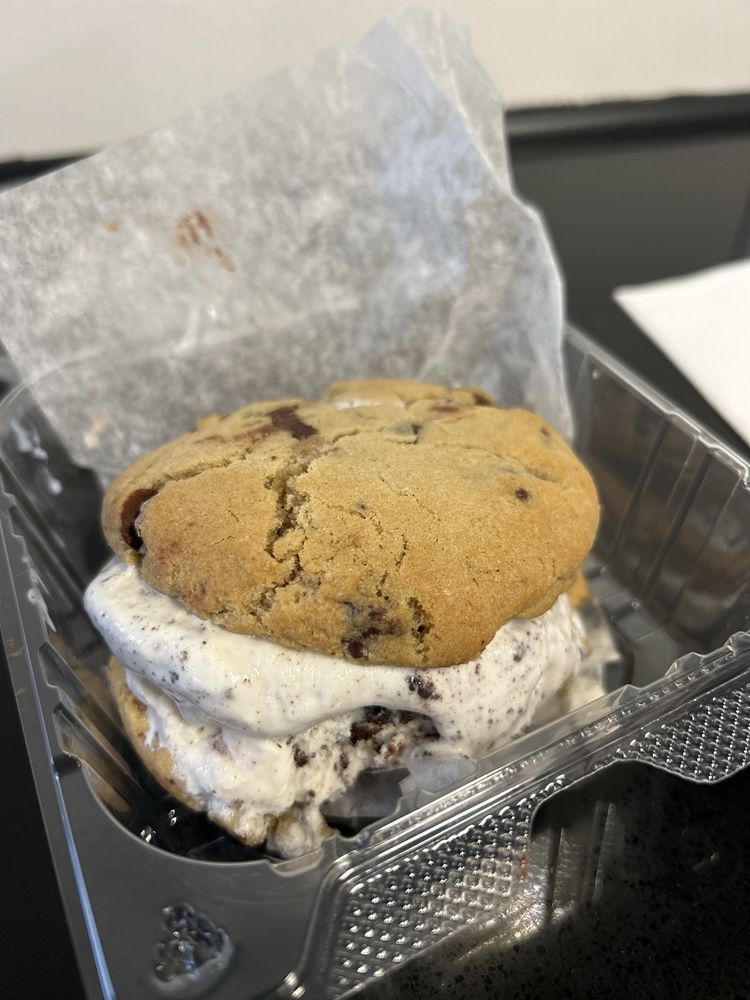 Chocolate chip cookie ice cream sandwich in a clear plastic container.