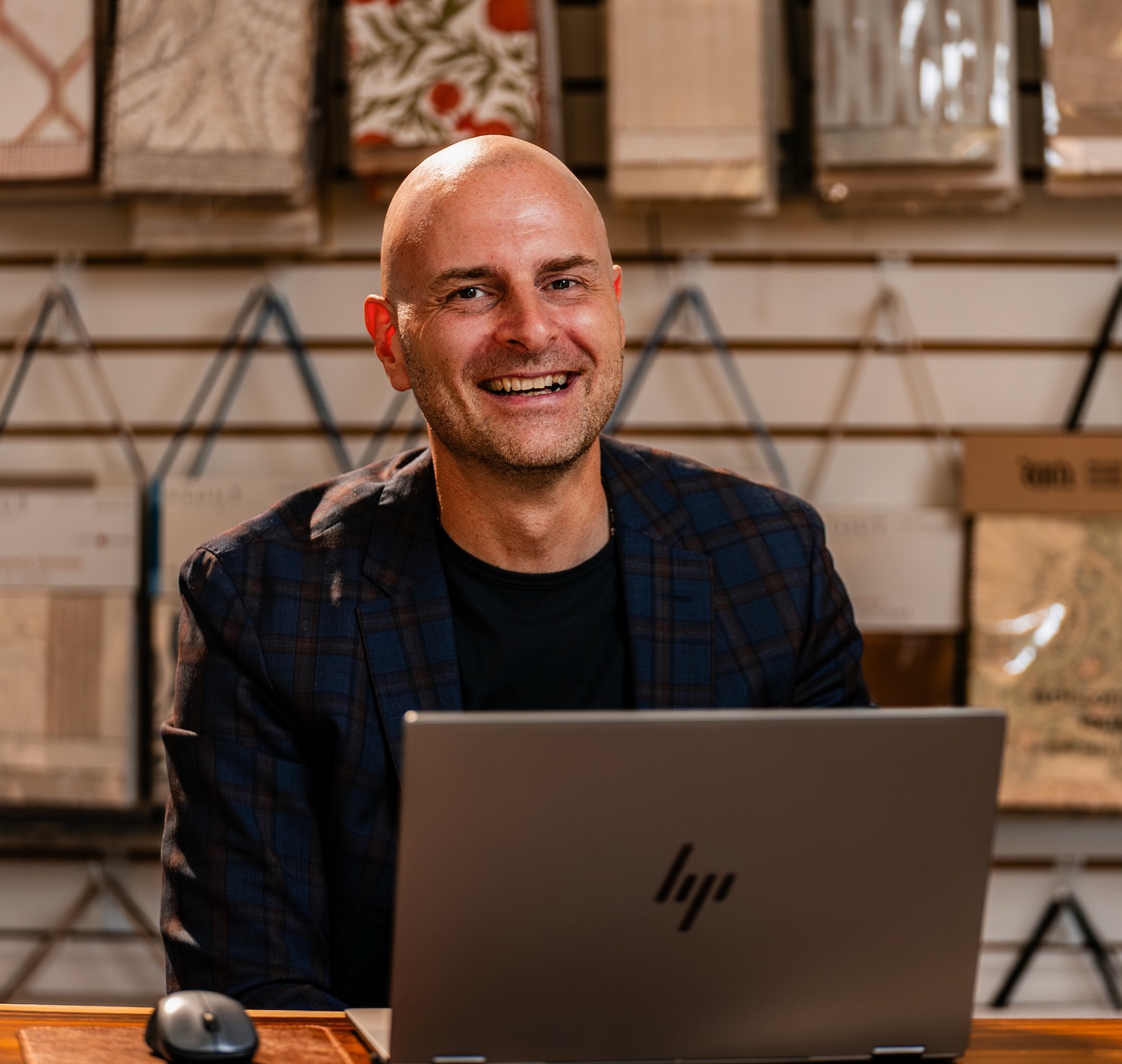 Tibor Farkas at his showroom desk in front of a wall of fabric and shade samples