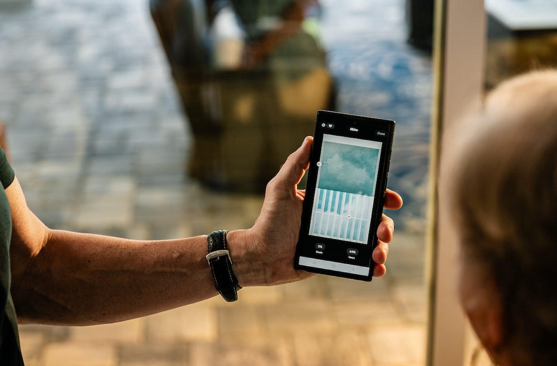 Hand holding a phone app that sets shade and vane position for motorized window coverings