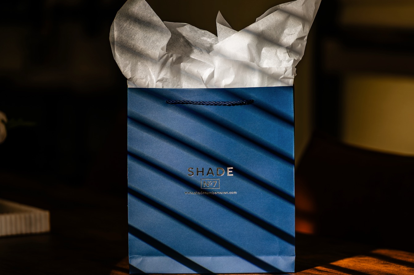 Shade No. 7 gift bag with tissue paper on a table in striped window light
