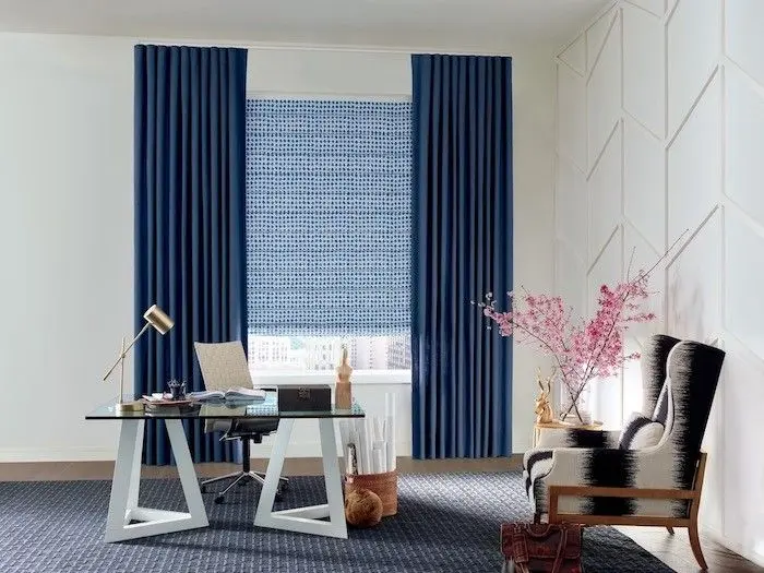 Navy custom drapery panels framing a patterned blue roller shade in a home office
