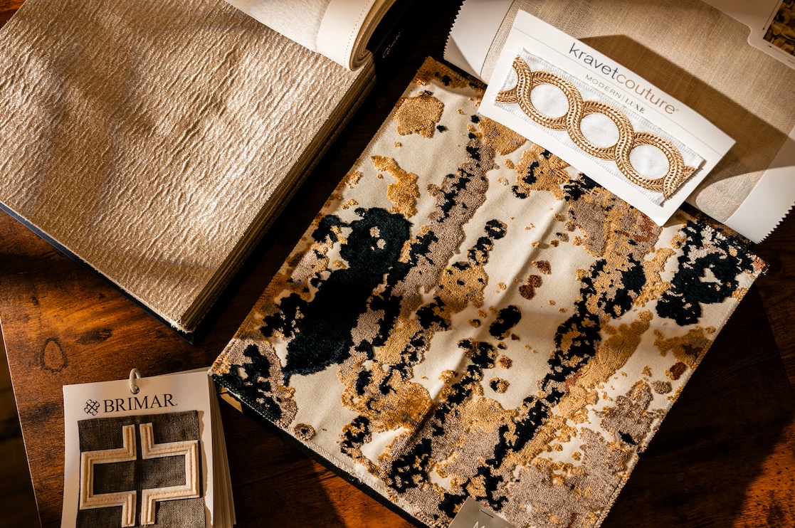Home decor fabric swatches and trim samples from Kravet Couture and Brimar on a wood table