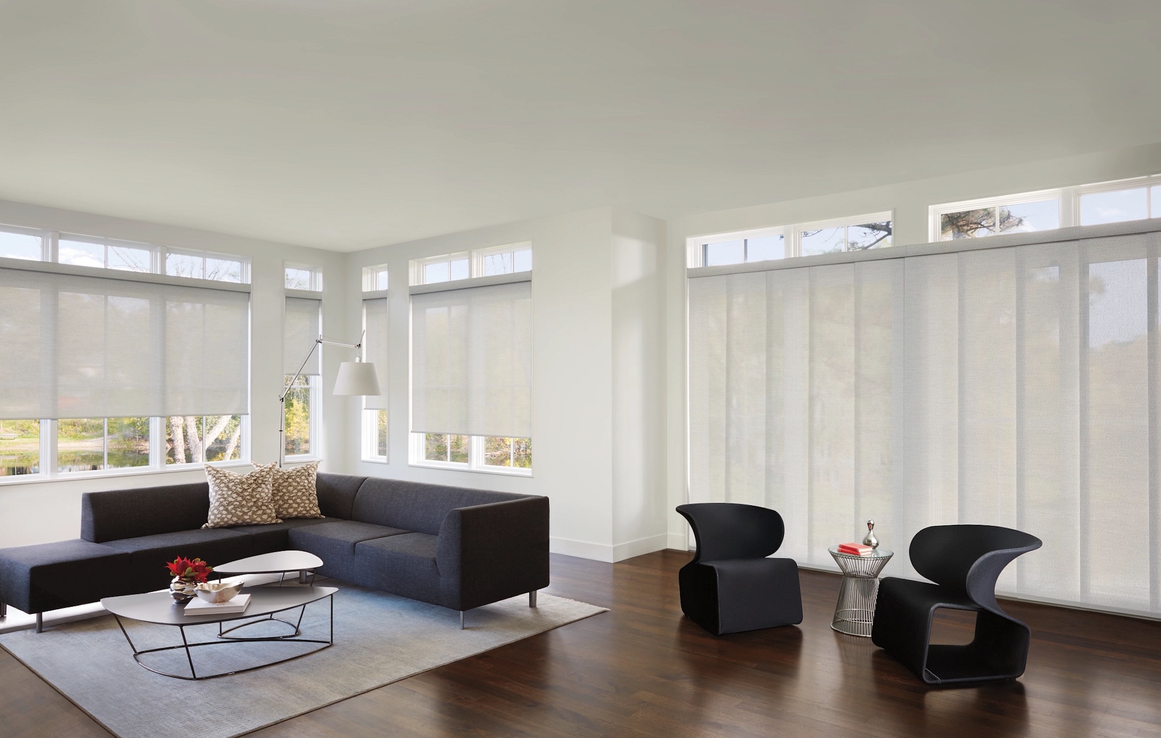 Sheer roller shades and a wide sliding panel track shade in a modern white living room