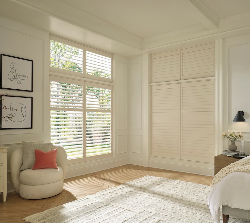 Cream plantation shutters on bedroom windows and matching louvered closet doors