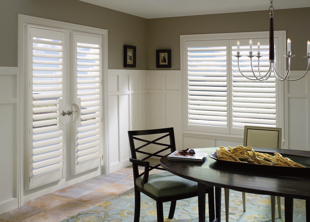 White shutters on dining room French doors and a window beside a dark wood table