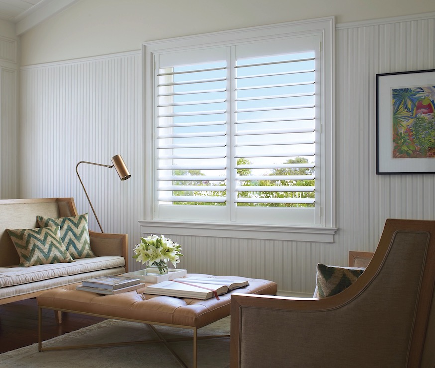 White plantation shutters with wide louvers on a beadboard sitting room window