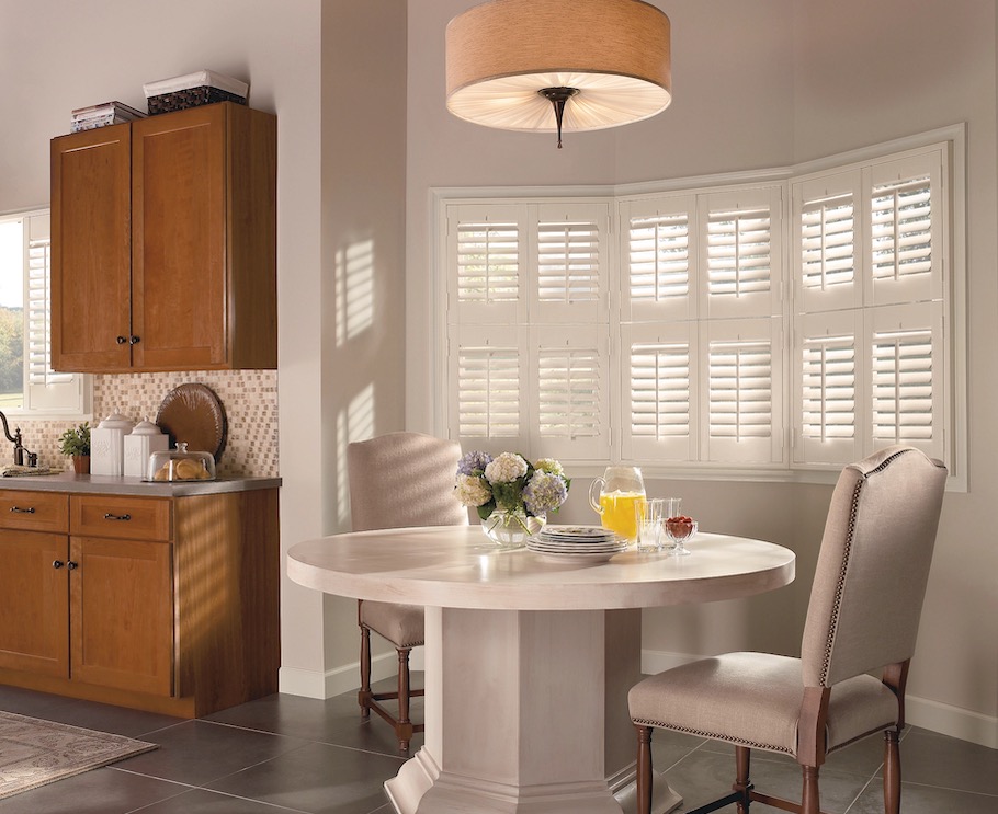 White plantation shutters on a bay window in a dining nook