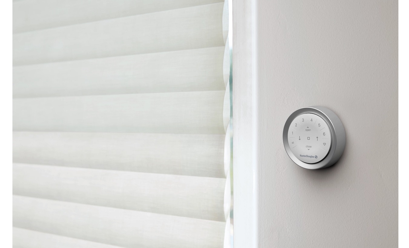 Hunter Douglas PowerView wall remote beside a cream pleated Sonnette shade