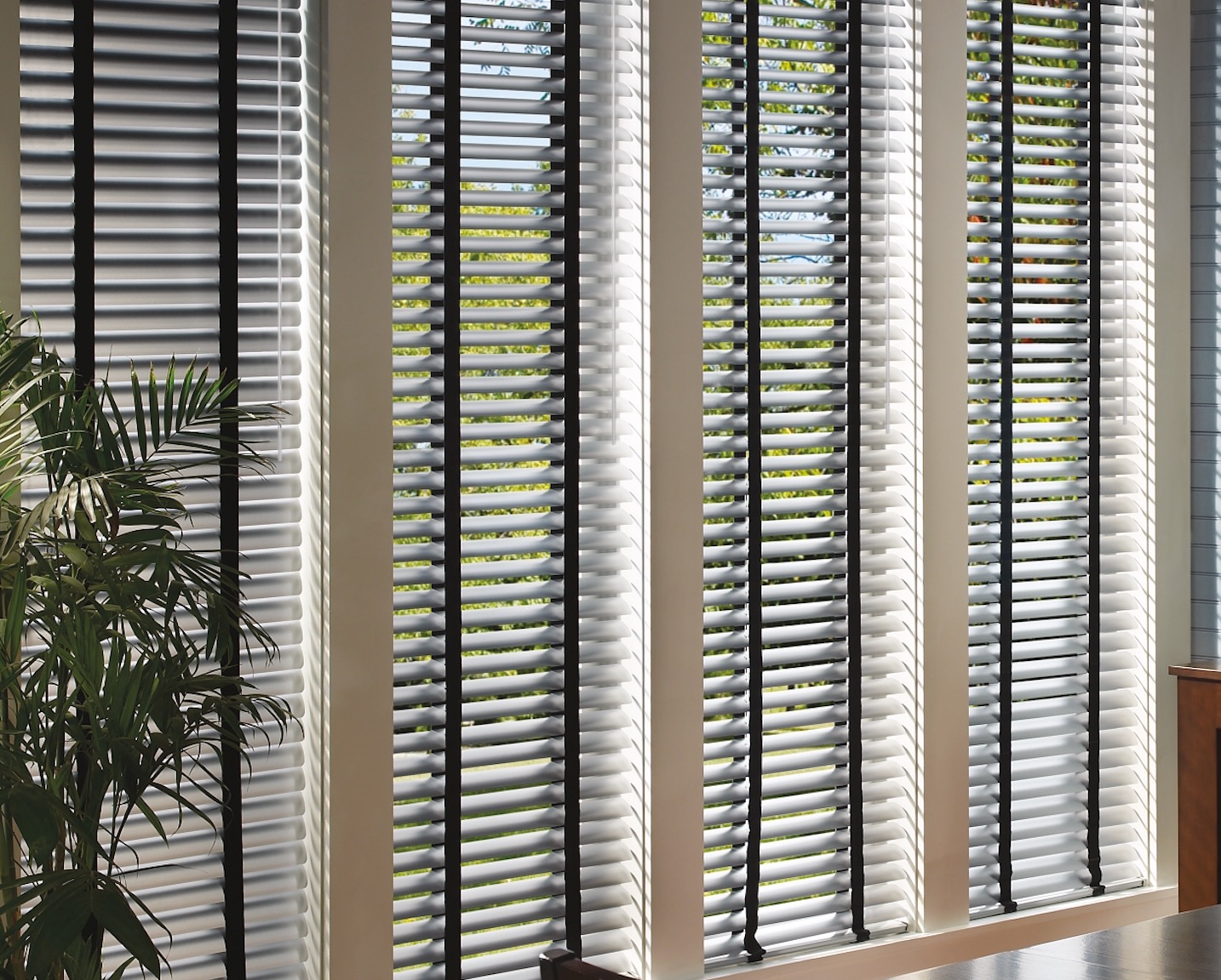 White horizontal blinds with black cloth tapes across a bank of tall narrow windows