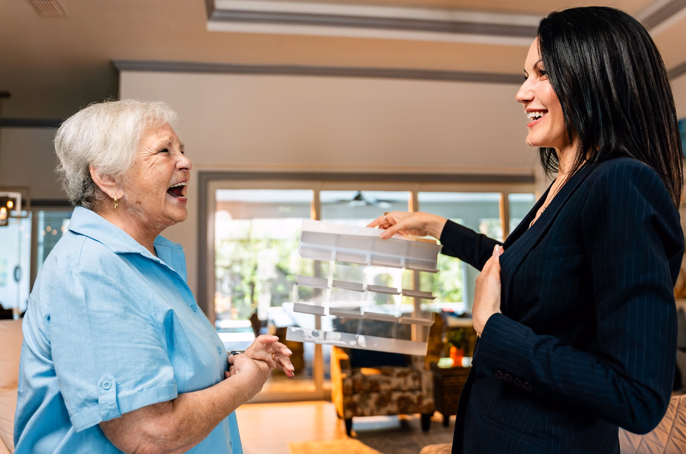 Consultant showing a shade sample to a laughing homeowner during an in-home estimate