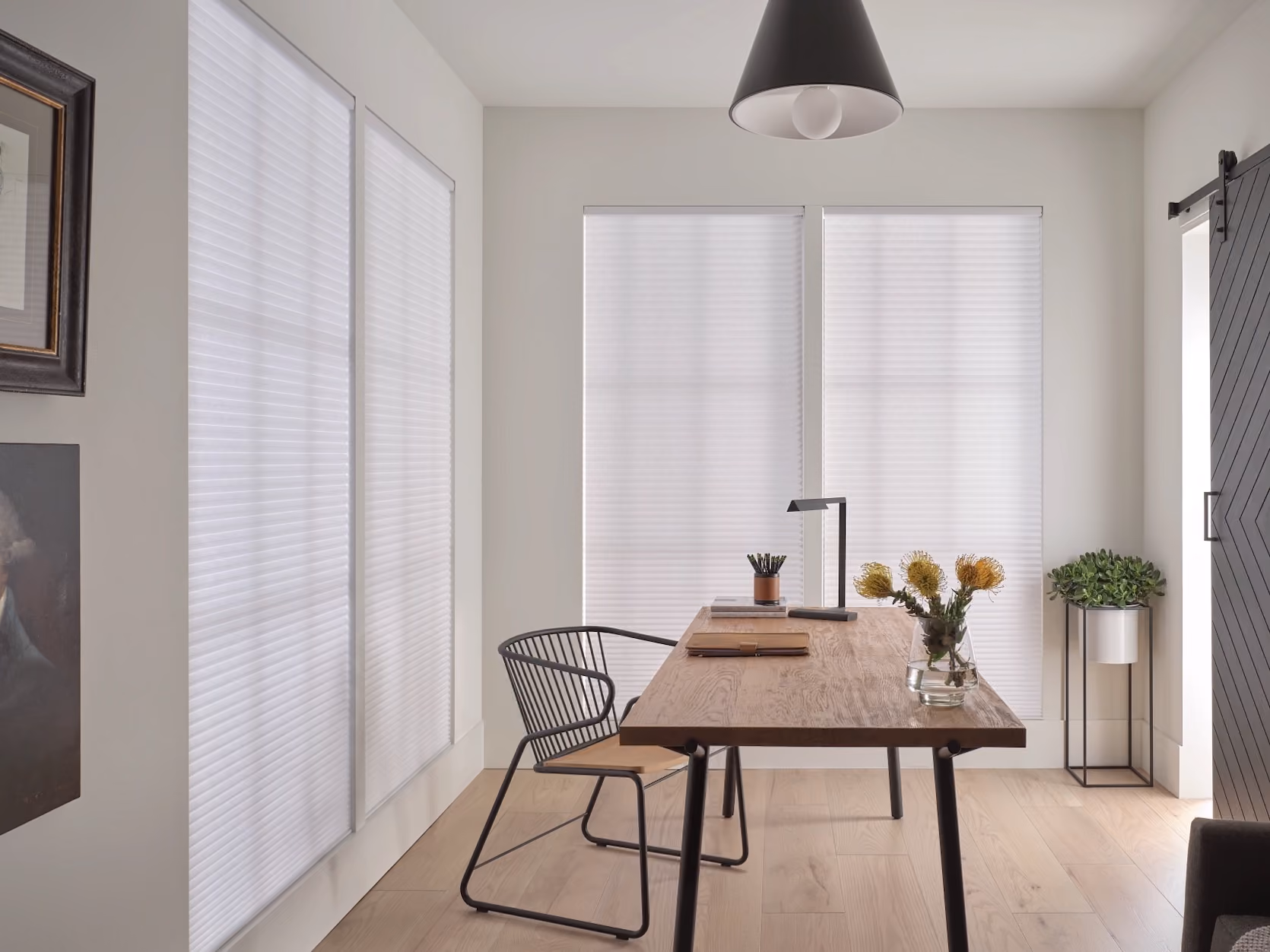 White cellular honeycomb shades on home office windows beside a wood desk
