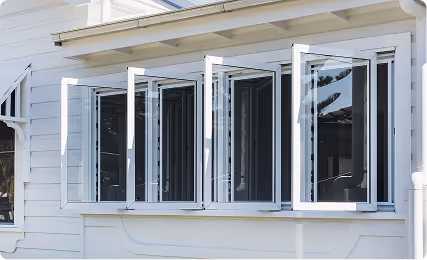 White casement windows partially open on a white house exterior.
