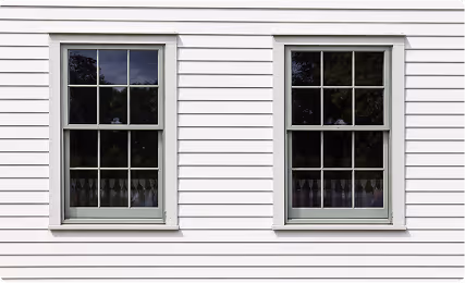 Two white double-hung windows with divided panes set in white horizontal siding.