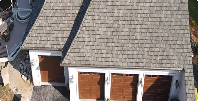 Aerial view of a house roof with grey shingles and a three-car garage with brown doors.