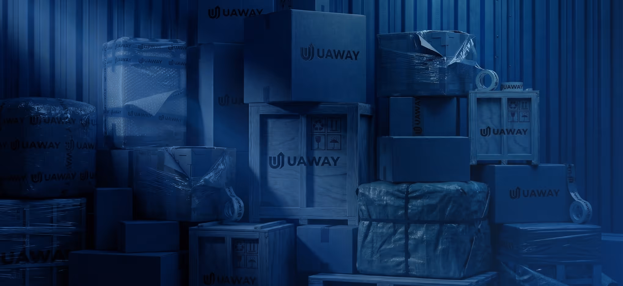 Stack of various cardboard and wooden boxes with UAWAY branding in a dimly lit storage area.