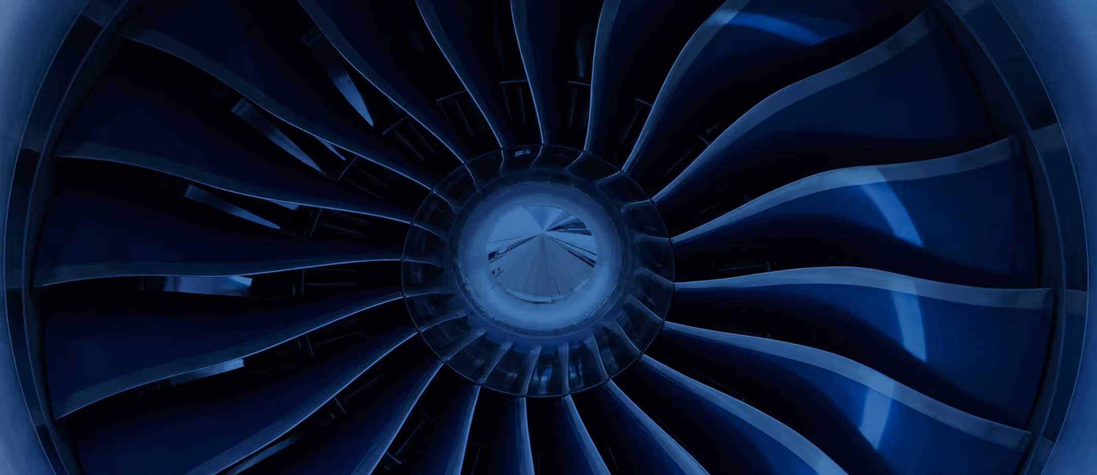 Close-up of an aircraft jet engine fan with curved blades illuminated in blue light.