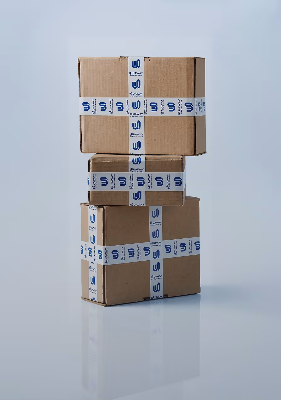Stack of three cardboard boxes sealed with white tape branded 'UAWAY' on a light reflective surface.