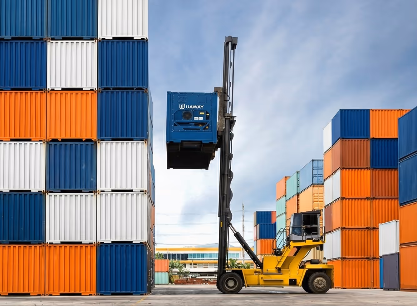 Yellow forklift lifting a blue UAWAY container among stacked orange, white, and blue shipping containers outdoors.