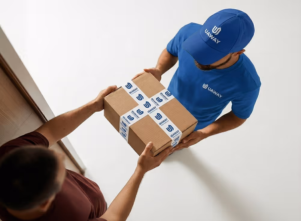 Delivery person in blue UAWAY uniform handing a branded cardboard box to a customer.
