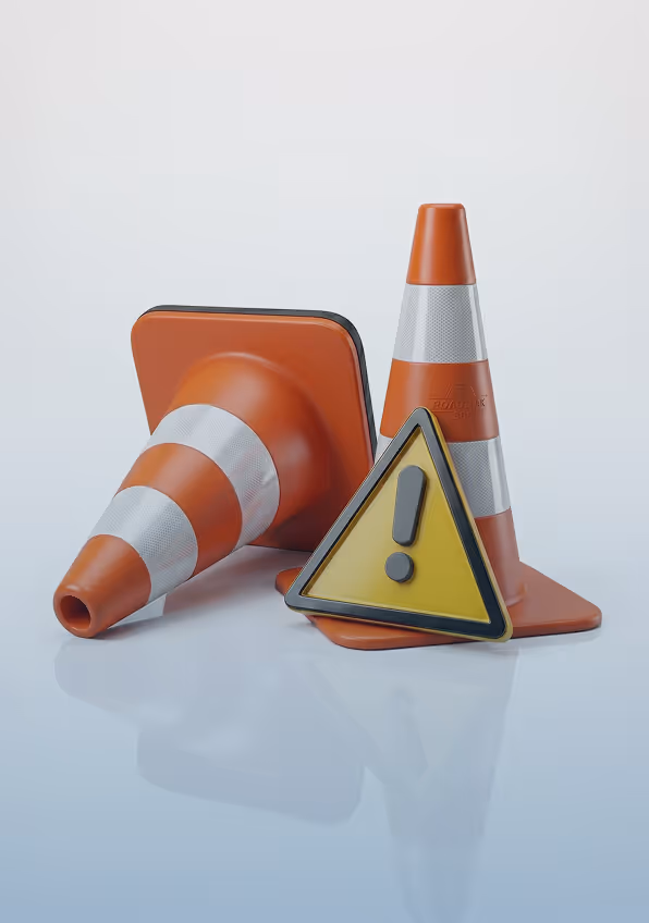 Two orange traffic cones, one upright and one on its side, with a yellow triangular warning sign displaying an exclamation mark.