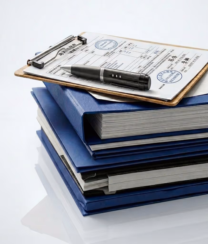 Stack of blue binders with a clipboard holding a document and a black pen on top.