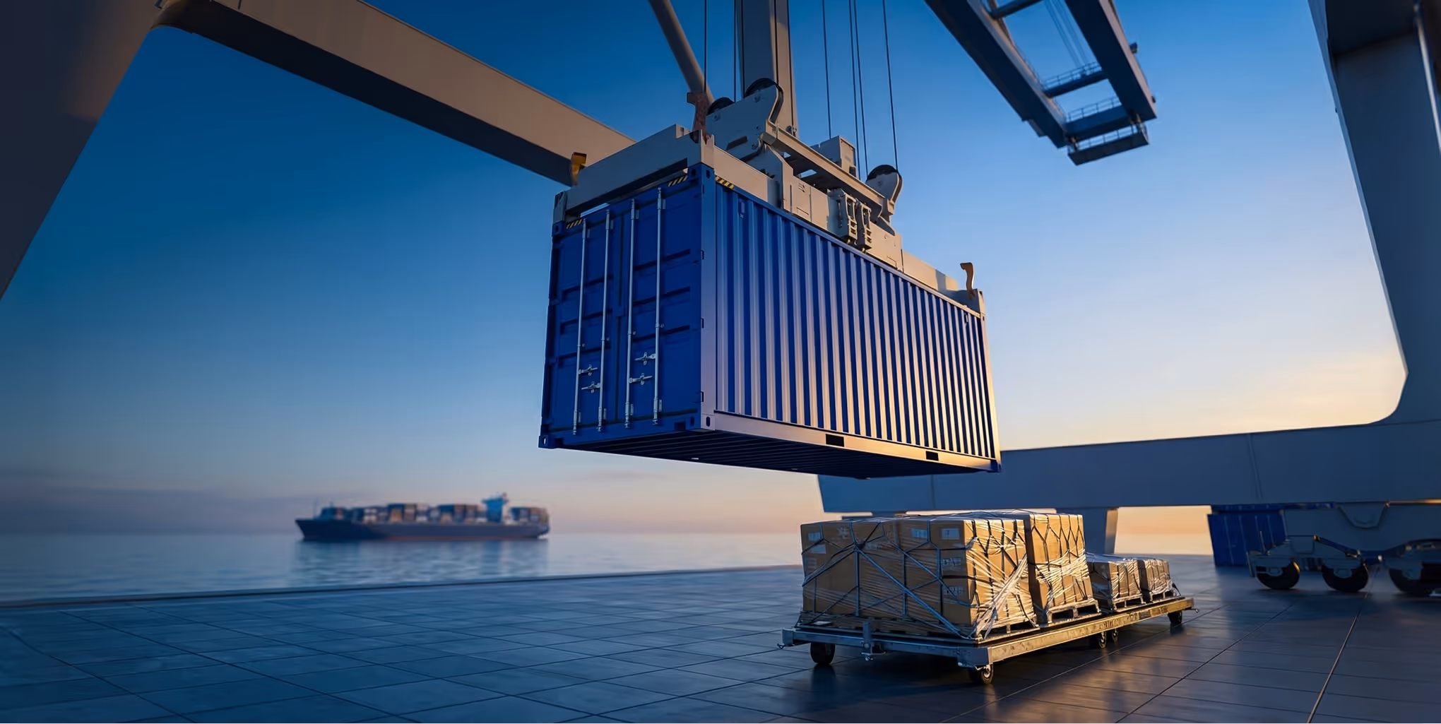 Blue shipping container being lifted by crane at dock with cargo ship in the background at sunset.