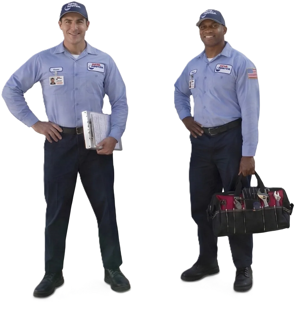 Two male plumbers in blue uniforms and hats, one holding a clipboard and the other holding a tool bag.