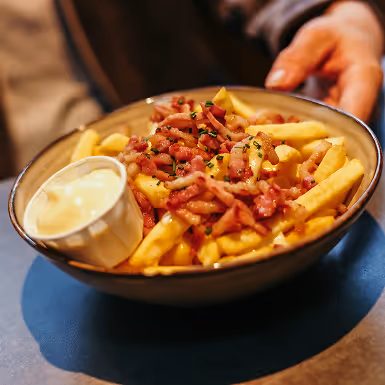 Schaal met frietjes, knapperige spekjes en een kleine portie mayonaise.