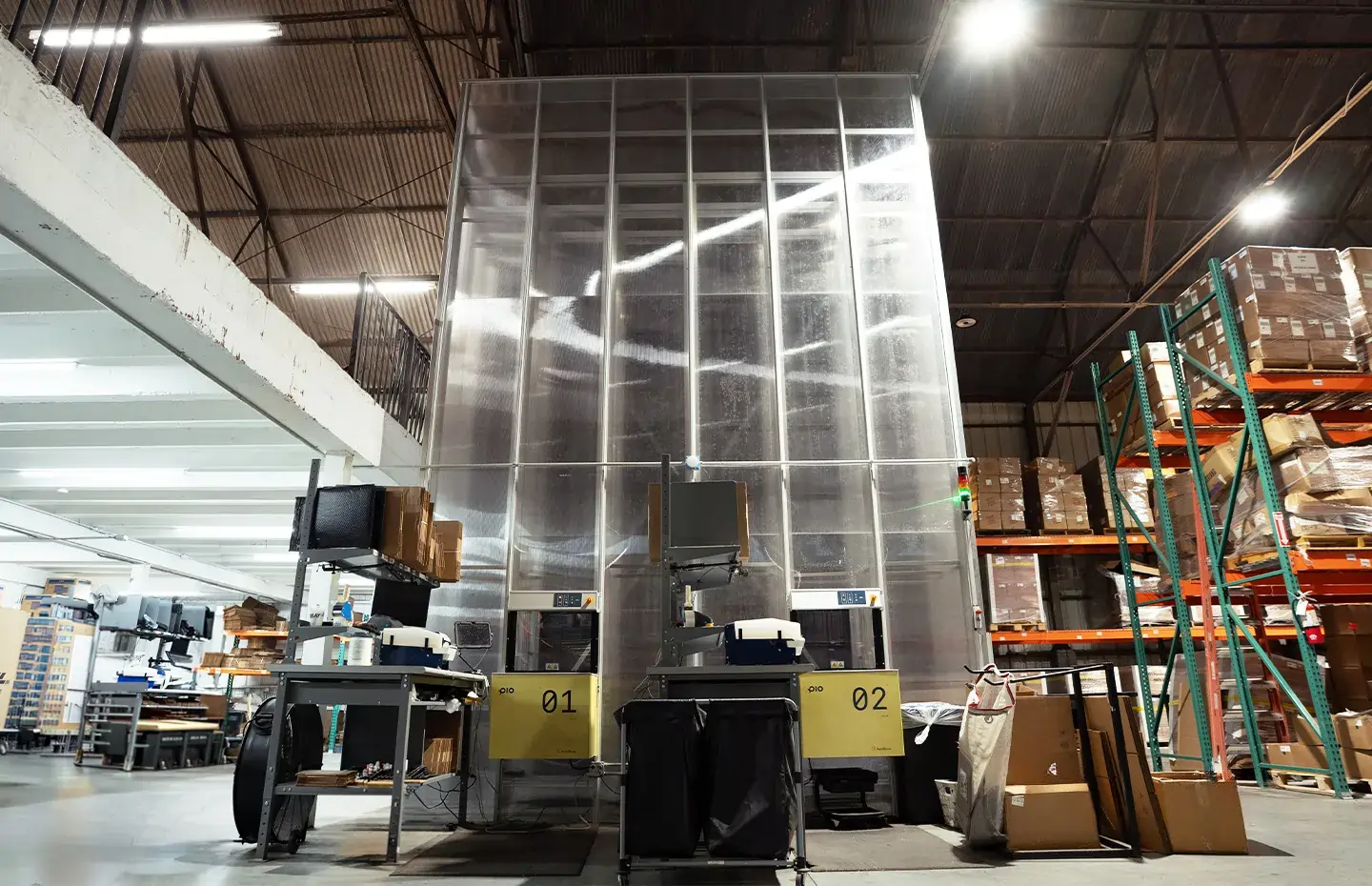 Two packing stations labeled 01 and 02 in a spacious warehouse with stacked boxes on shelves.