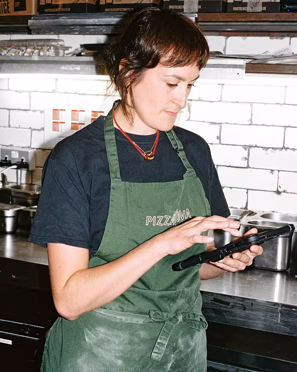 Pizzanova kitchen staff member using a tablet to manage restaurant operations with Nory software