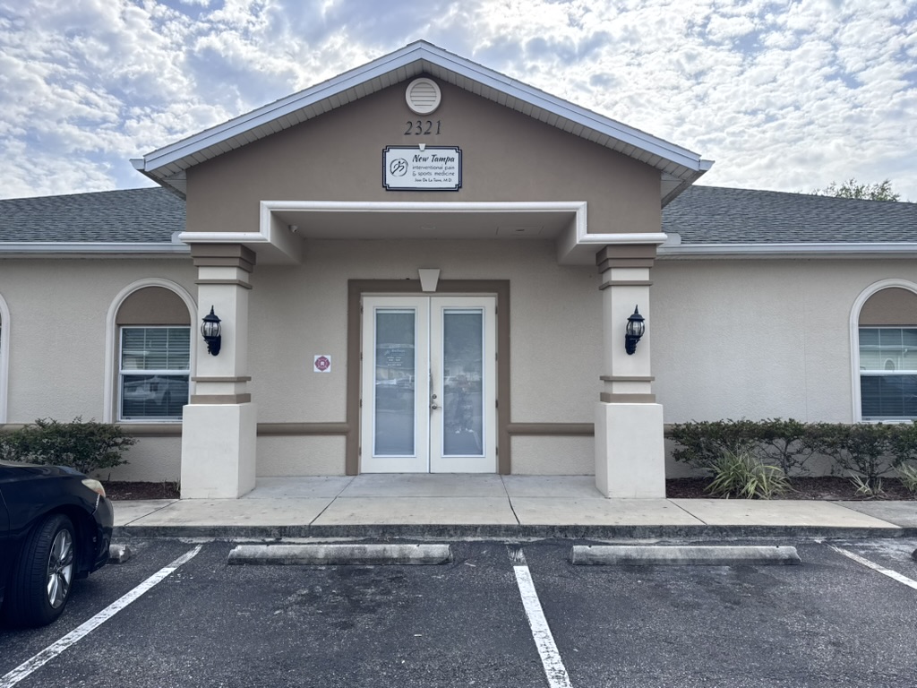 Entrance of New Tampa Wellness Clinic with double glass doors and parking spaces.