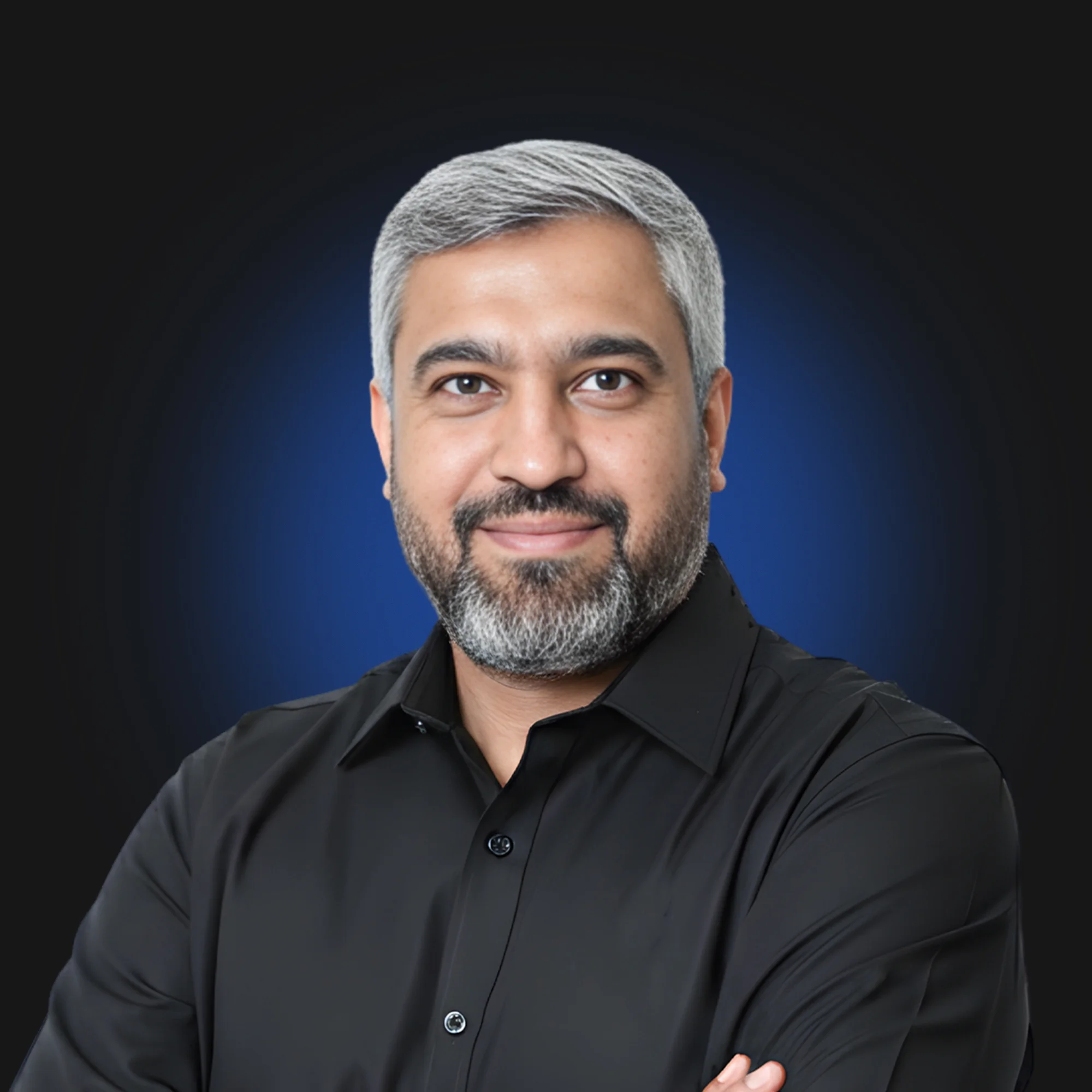 Smiling man with gray hair and beard wearing black shirt, arms crossed, blue glow background.